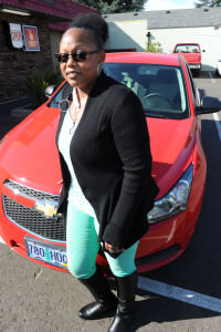 Laquesha Muldrew poses with her 2014 Chevy Cruze in front of Boss Hawg’s Bar ‘N’ Grill, the bar near her home that she and family members frequent. In June, she won the car as part of bar owner Larry Olsen’s contest to reward customers. STAFF/2015